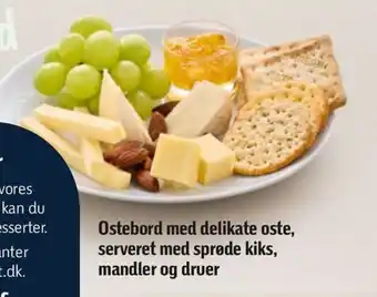 Ostebord med delikate oste, serveret med sprøde kiks, mandler og druer