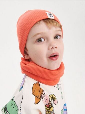 Bordázott kötésű beanie sapka rátéttel
